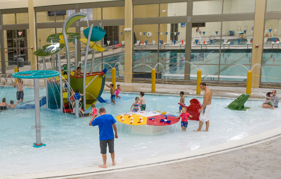 Families playing in aqua play pool environment.
