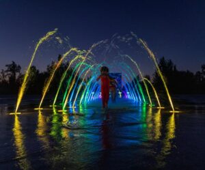 Girl running through LED Arch Jets at night