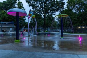 Pink LED accent lights illuminate water play products at Lions Park splash pad in Urbandale, Iowa