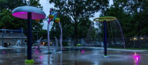 Pink LED accent lights illuminate water play products at Lions Park splash pad in Urbandale, Iowa