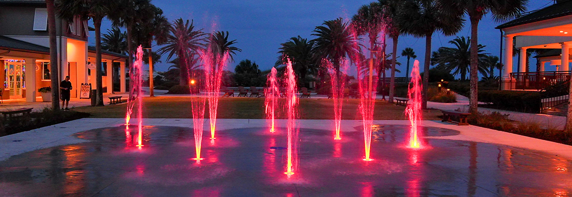 Wide shot of Jekyll Island splash pad at night with pink LED lights