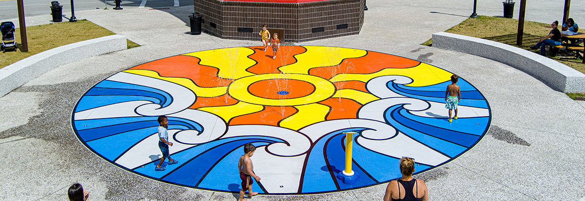 Wide shot of Tanger Outlets splash pad showing colorful play surfacing