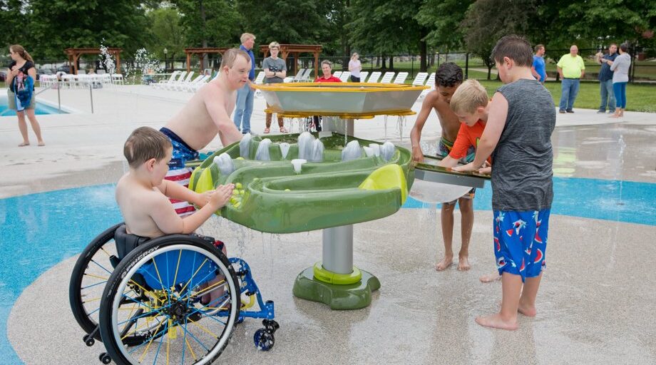 children play on an activity table at a splash pad