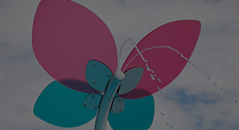 Looking up at a flower-shaped overhead water feature at a spray park