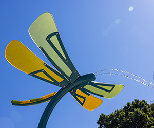 Looking up at a dragonfly-themed spray feature at a splash pad