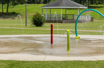 Wide shot of Byhalia Walking Trail Splash Pad showing water spray arch and ground sprays