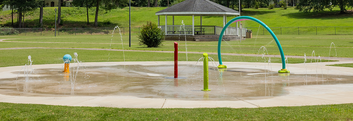 Wide shot of Byhalia Walking Trail Splash Pad showing water spray arch and ground sprays