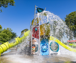 A large splash pad structure with water spraying from a bucket at the top