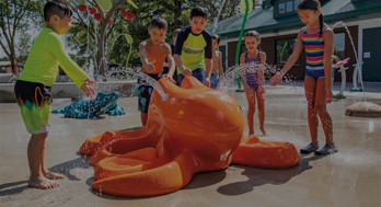 children holding their hands in the spray from an orange splash play animal aqua form