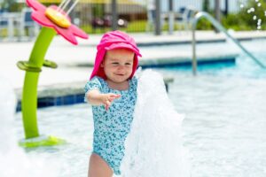 A toddler reaches toward a bubbling ground spray