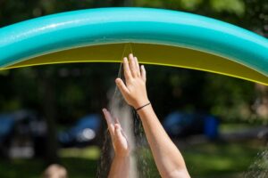A child's hands reach up to feel the mist coming from an arched splash pad feature