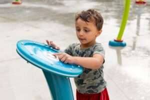 Boy presses the aquavator at a splash pad