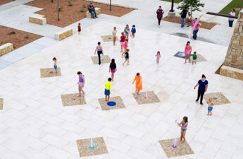 wide shot of people playing on a splash pad with ground sprays