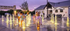Little girl looks at camera while standing on LED lighted ground spray at splash pad